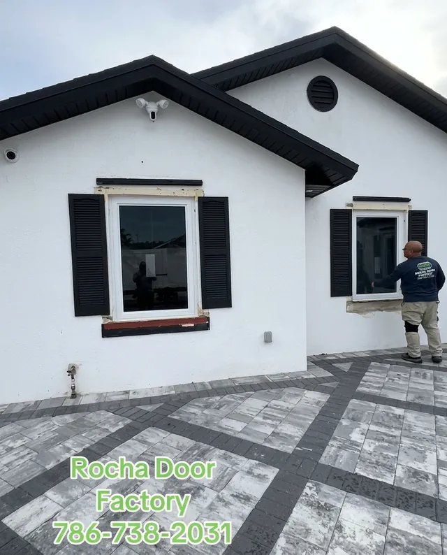 Rocha Door Factory installer fitting impact windows on a white house